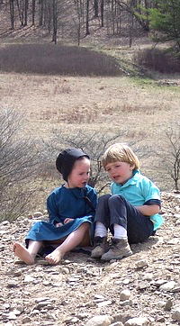 Amish children sitting on a hill.